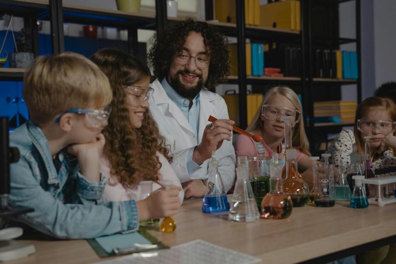 Students in a science class watch a chemistry experiment with colorful liquids.